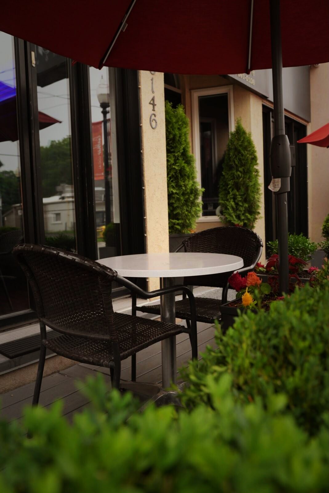 The AGI patio on Main Street — table under a red umbrella beside the cedars